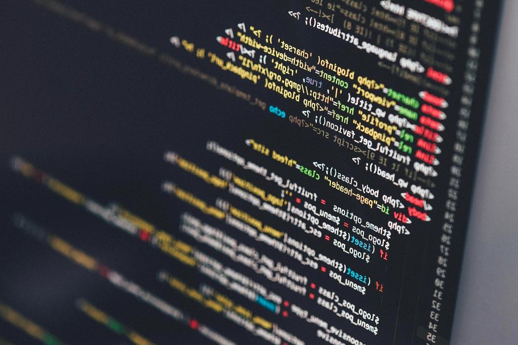 Person coding software on a laptop with lines of code visible